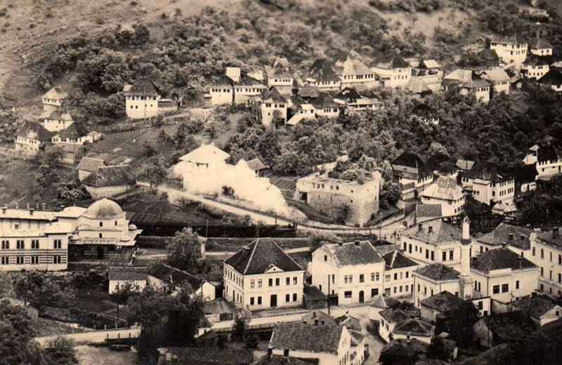 A black-and-white historic aerial view of a town with a steam train passing through.