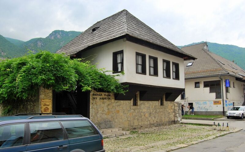 A traditional Ottoman-style house with green hills in the background.