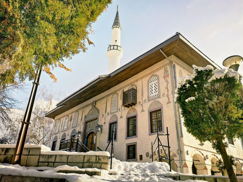 The decorated facade and minaret of the Šarena džamija in Travnik covered in winter snow.