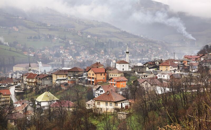 A misty overview of residential neighborhoods and hillside slopes in Travnik.
