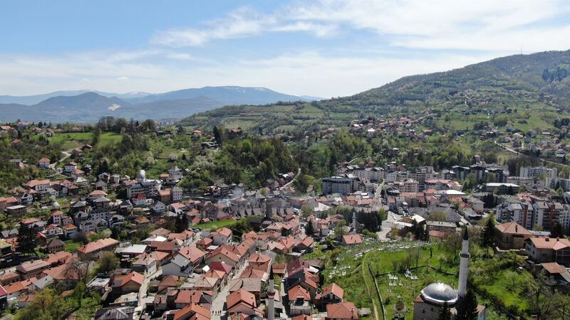 A wide view overlooking the red roofs, mosques, and surrounding hills of Travnik.